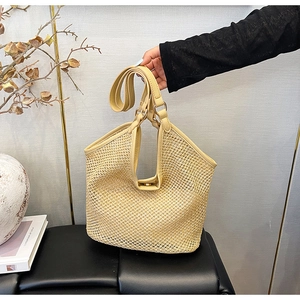 Détail d'un sac cabas en paille tressée beige avec anses en cuir synthétique et fermoir aimanté