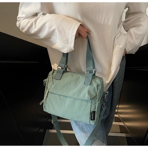 Detail of mint green nylon handbag featuring adjustable shoulder straps and side brand tag