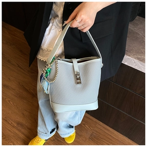 Detail of light blue bucket bag with woven texture, horse charm, and green ribbon