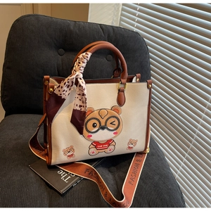 Detail of cute bear tote bag with leopard scarf and wide shoulder strap on grey sofa
