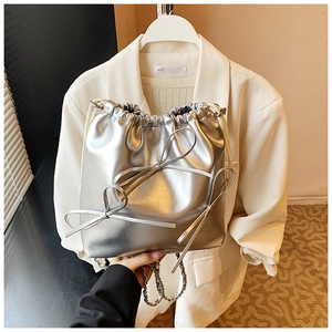 Macro shot of silver metallic bucket bag with butterfly knots and sleek chain strap
