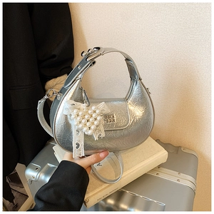 Detailed shot of silver crescent hobo bag featuring metallic pleats and heart pearl charm