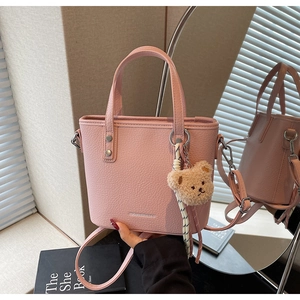 Pink lychee texture leather bucket bag with top handles and a cute plush bear pendant accessory