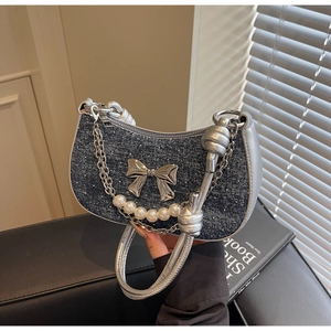 Close-up of crescent denim bag with silver bow, metal chain, and pearl details