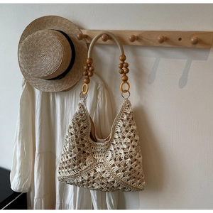 Detail of hand-woven straw tote with wooden bead handle and yellow decorative ring