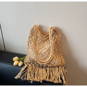 Detail of bohemian woven tote bag featuring hollow mesh pattern and long fringe tassels