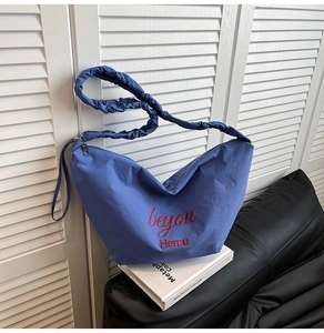 Detail of blue nylon crossbody bag with ruched handle and red beyou Hemu branding