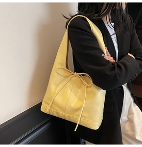 Détail du sac hobo jaune avec un cordon à nœud élégant et une texture en cuir synthétique