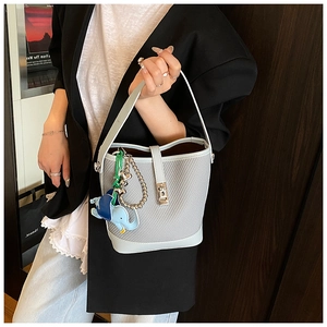 Detail of light blue bucket bag with woven texture, metal turn-lock and cute elephant charm