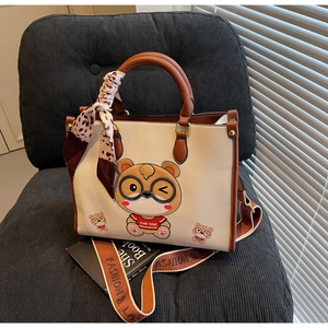 Detail of tote bag with cartoon bear, leopard scarf handle, and wide strap on chair