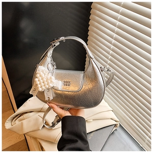 Detail view of silver pleated hobo bag with pearl heart charm and lace bow accessory