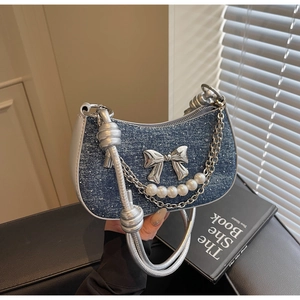 Detailed shot of denim blue hobo bag with metallic bow and pearl chain decoration