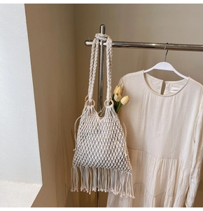 Detail of woven cream macrame bag featuring wooden rings and long decorative tassels