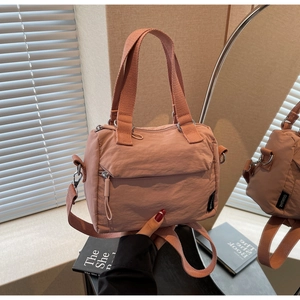 Detail of dusty rose nylon handbag with reinforced webbing handle and front zipper pocket
