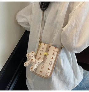 Detail of cream crossbody bag featuring all-over teddy bear print and matching 3D charm