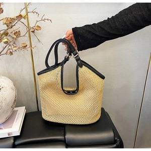 Vue détaillée du sac cabas en paille tressée avec poignées et finitions en cuir noir