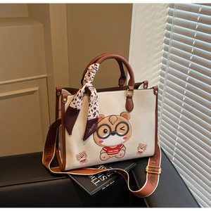 Close-up of cream textured leather tote bag with cartoon bear and leopard silk scarf