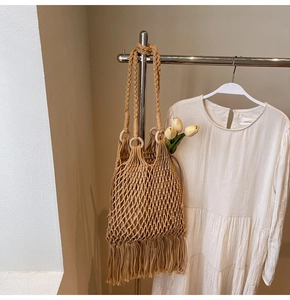 Detail of hand-woven hollow knit bucket bag with long tassels and spiral shoulder strap