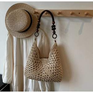 Bohemian straw tote bag detail with intricate hollow crochet texture and wooden bead handles