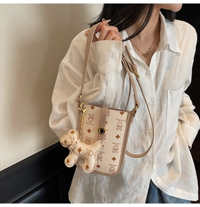 Detail of cartoon bear print shoulder bag with adjustable strap and bear charm accessory