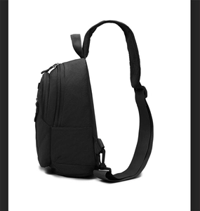 Detail view of the black matte nylon chest bag featuring dual zippers and side pocket
