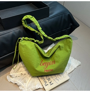 Detail of light green nylon tote bag with ruched handle and red brand lettering