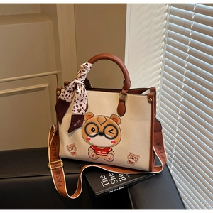 Detail of a beige tote bag with a cartoon bear print and stylish leopard scarf on handle