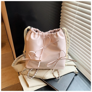 Detailed shot of pink leather bucket bag with ribbon bows and drawstring design