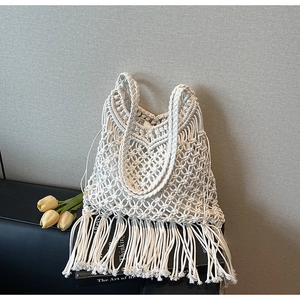 Detailed close-up of woven bohemian tassel tote bag with hollow knit patterns