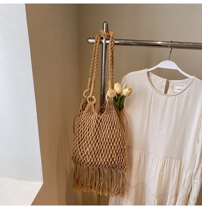 Detail of a khaki woven bucket bag with long tassels, featuring intricate mesh texture