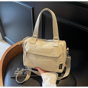 Detailed close-up of beige nylon handbag with SHUNUO woven label and adjustable strap