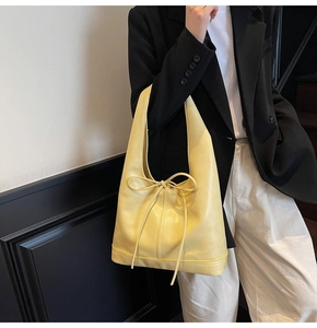 Détail d'un sac cabas en cuir PU jaune avec un nœud décoratif réglable sur le devant