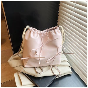 Detail of pink drawstring bucket bag with decorative 3D bows and gold chain strap