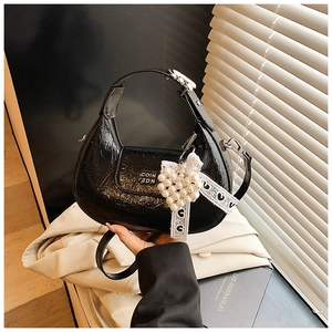Detail of black pleated leather crescent bag with pearl heart charm and silk ribbon