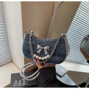 Detail of blue denim hobo bag with silver metallic bow and pearl chain decoration