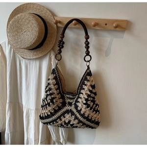 Detail of woven straw tote bag with brown wooden beads and bohemian geometric pattern
