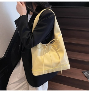 Détail du sac hobo jaune clair avec un nœud en cuir délicat et une finition lisse