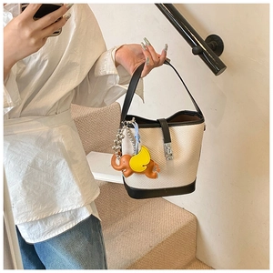 Detail of cream bucket bag featuring black leather trim and a cute orange elephant charm