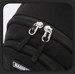 Close-up of black nylon bag detailing dual silver metal zippers and MACHIN logo