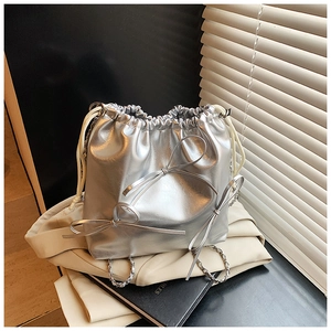 Close-up of metallic silver bucket bag featuring three 3D bow ties and chain strap