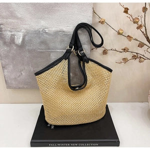 Détail du sac cabas en paille tissée avec finitions en cuir noir et boucles dorées