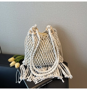 Detail of white handmade woven cotton bag with tassels and round wooden handle