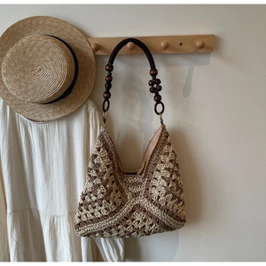 Detail of woven straw tote bag with brown geometric patterns and wood bead straps