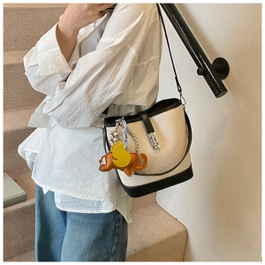 Detail of woven bucket bag with leather trim, silver lock, and cute elephant charm