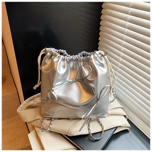 Detail of silver metallic drawstring bucket bag with bow accents and chain strap