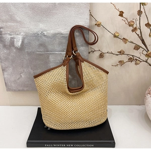 Détail du sac cabas en paille avec poignées en cuir marron et anneaux métalliques chic