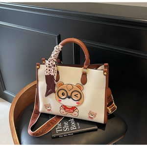 Detail of cute bear tote bag showing cream leather, brown trim, and logo wide strap