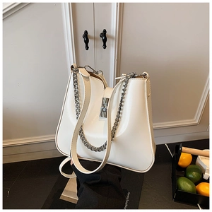 Close-up of cream leather bucket bag with silver chain detail and sleek metallic turn-lock