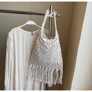 Detail of bohemian hollow woven tote bag featuring long tassels and cotton rope texture