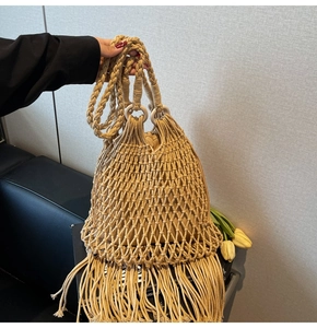Close-up of woven straw bucket bag showing hollow mesh detail and long fringe tassels
